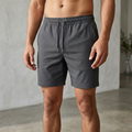 Close-up of a male model wearing trendy shorts, emphasizing fabric detail, texture, and fit against a neutral background.
